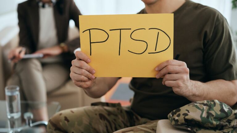 Veteran Holding Up Yellow Paper with PTSD Written On It