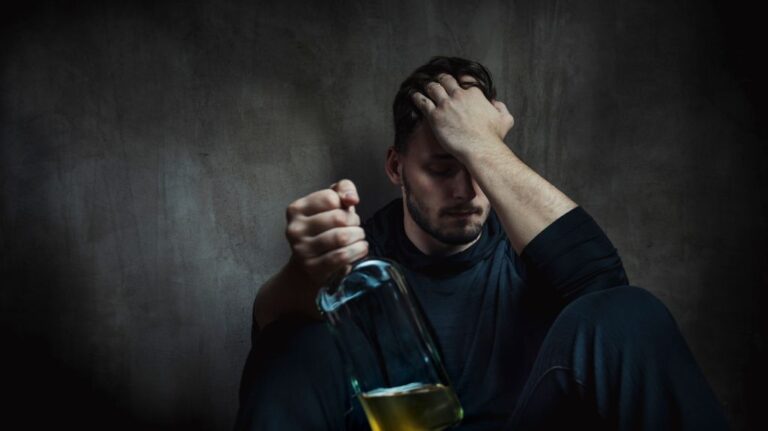 Man Sitting in the Dark Holding a Bottle
