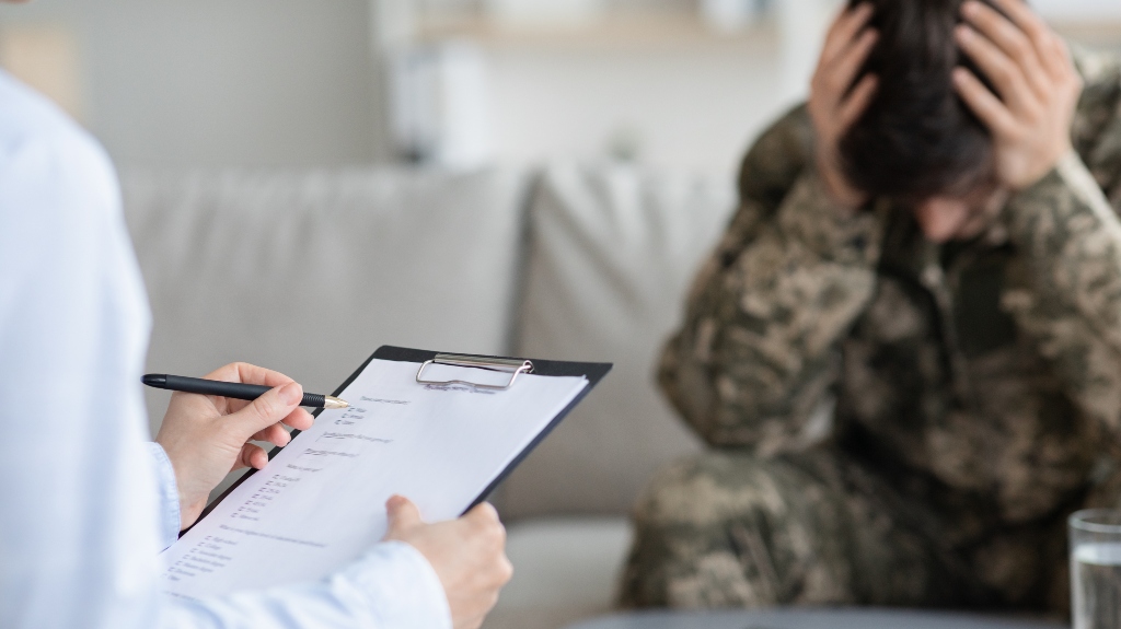 Distressed veteran attending therapy session with psychotherapist