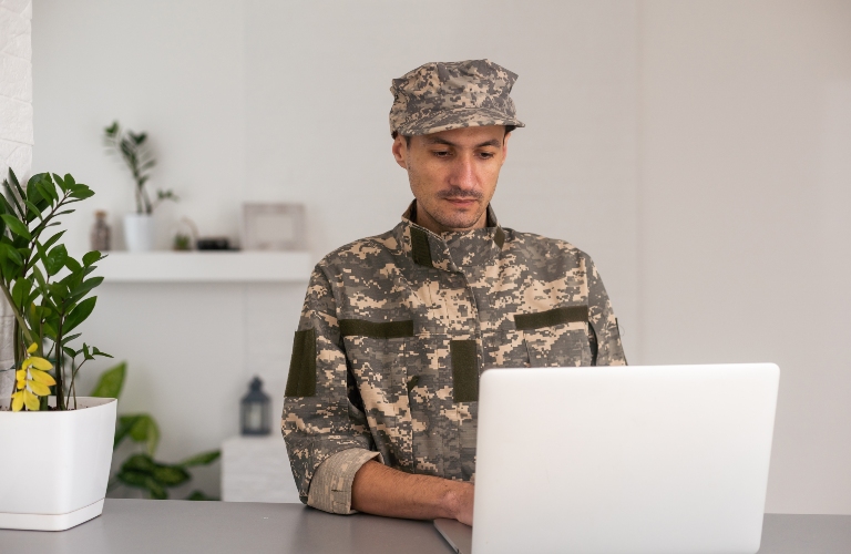 Soldier in camouflage uniform working on laptop